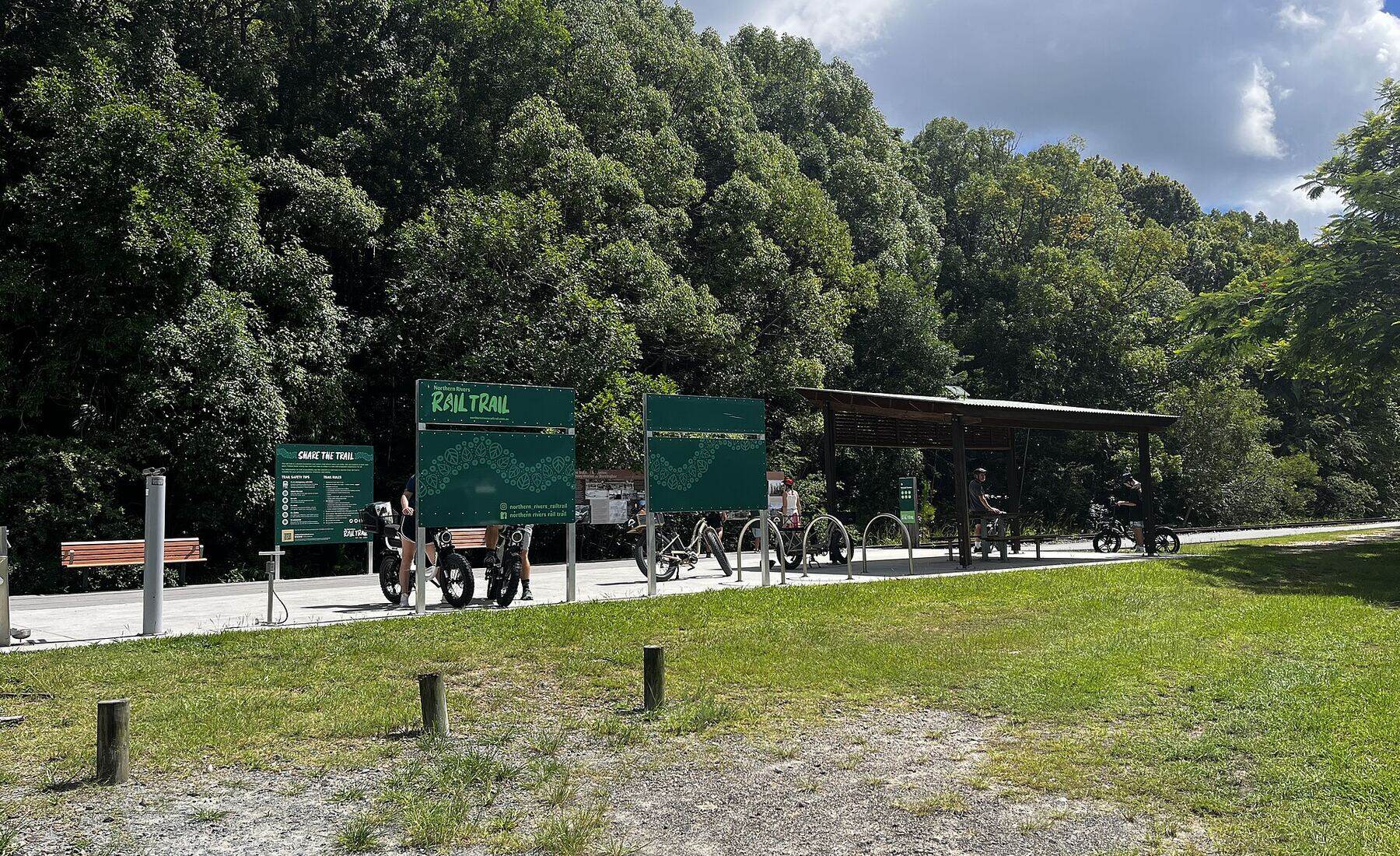 The Northern Rivers Rail Trail stop at Burringbar, with bike racks and green trail signs under a big summer sky
